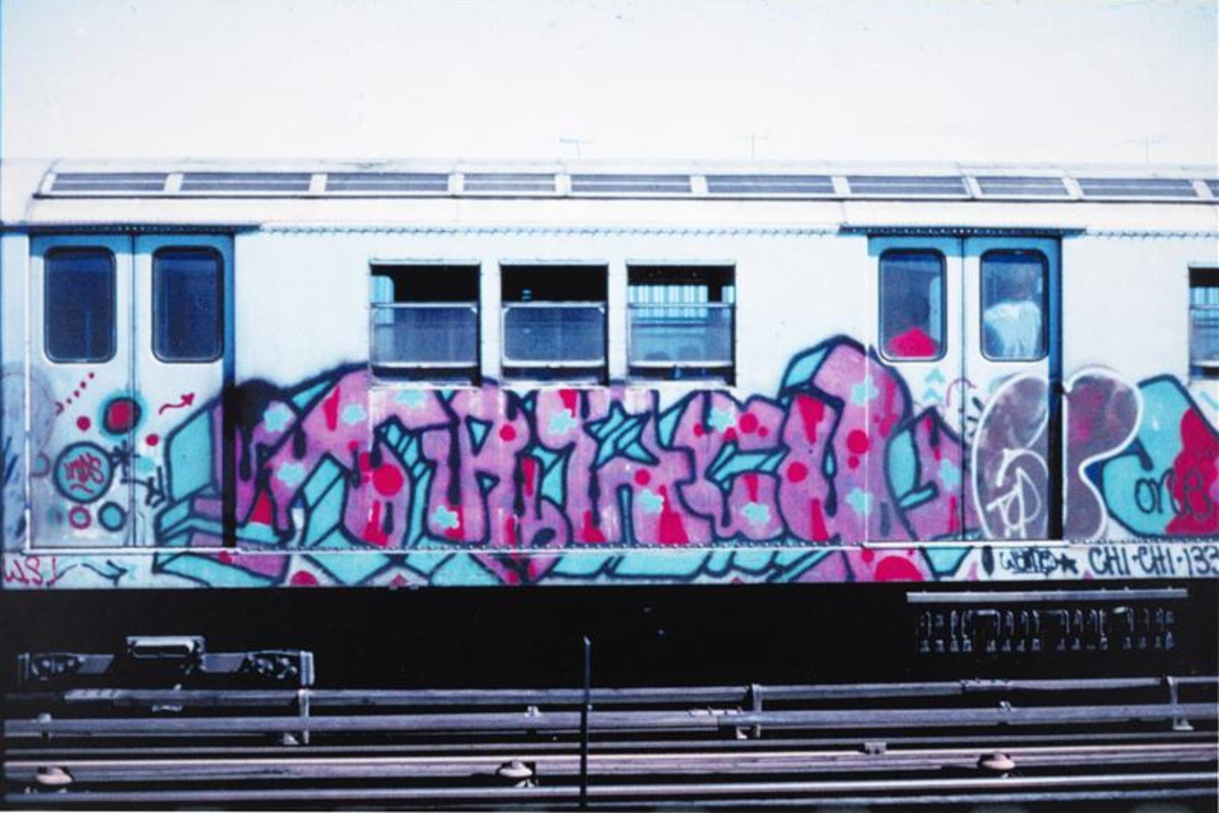 Image of Graffiti writing on a subway car on outdoor train tracks